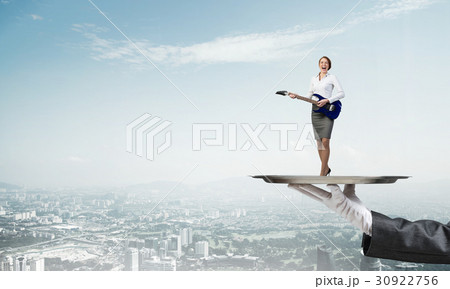 Attractive businesswoman on metal tray playing electric guitar against cityscape background 30922756