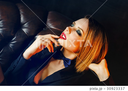 Femme fatale on leather couch 30923337