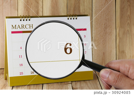 Magnifying glass in hand on calendar. 30924085