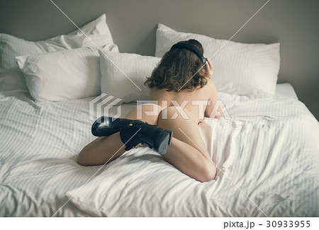 Beautiful naked girl lies on a bed in headphones Beautiful naked girl lies on a bed in headphones 30933955
