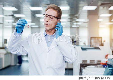 Serious practitioner holding phone near left ear 30938449