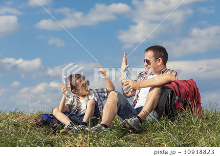 Father and son sitting in the field at the day time. 30938823