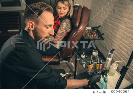 Calm male master putting color in tattoo machine 30940064