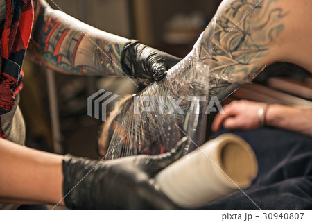 Woman enveloping tattoo arm of client 30940807