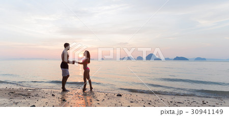 Couple Holding Hands On Beach At Sunset, Young Couple Holding Hands On Beach At Sunset, Young 30941149