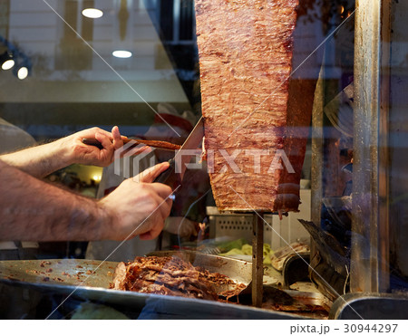 An arm moving to cut the kebab meat An arm moving to cut the kebab meat 30944297
