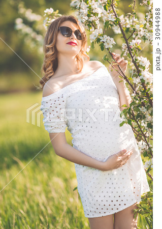 Happy pregnant young woman in white blossom garden Happy pregnant young woman in white blossom garden 30944988