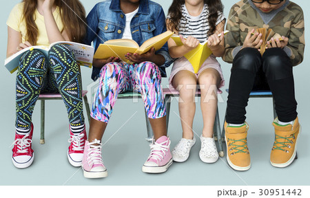 Diverse group of kids sitting in a row reading books 30951442