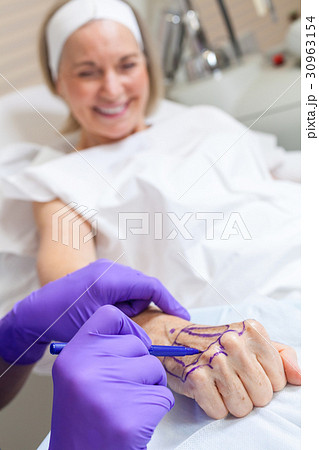 Plastic Surgeon Doctor Marks Hand of Senior Woman 30963154