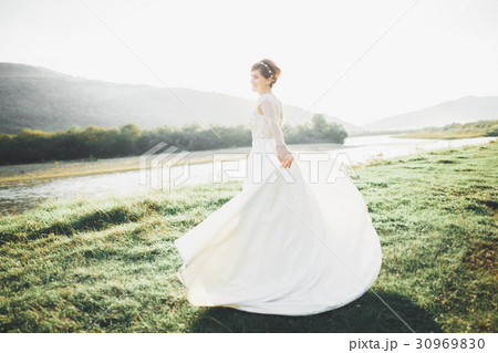 Bride in wedding dress posing on grass with 30969830
