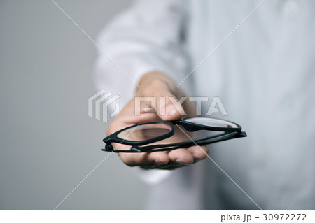 optician man bringing a pair of eyeglasses 30972272