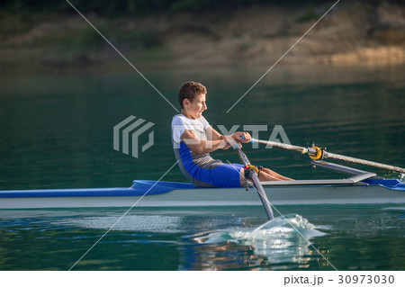 A Young single scull rowing competitor paddles on A Young single scull rowing competitor paddles on 30973030