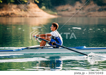 A Young single scull rowing competitor paddles on 30973049