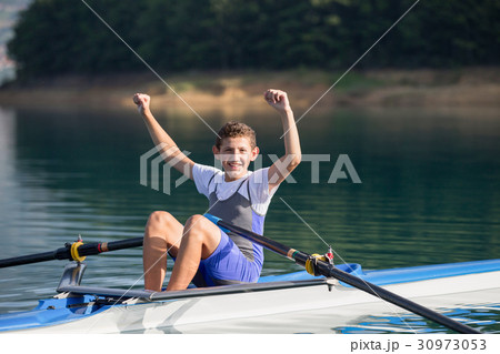 A Young single scull rowing competitor paddles on 30973053