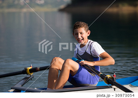 A Young single scull rowing competitor paddles on 30973054