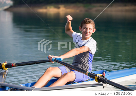 A Young single scull rowing competitor paddles on 30973056