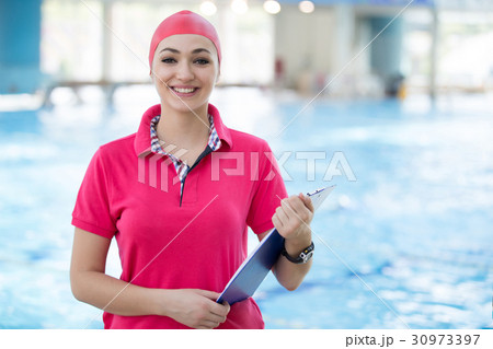 Fit female swimming trainer with tablet at the 30973397