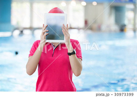 Fit female swimming trainer with tablet at the 30973399