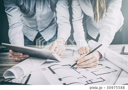 Designers discuss the sketches inside the house. Designers discuss the sketches inside the house. 30975588