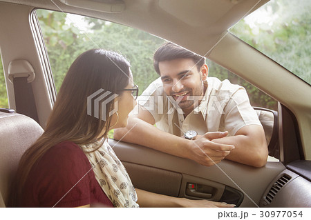Man leaning on car window talking to woman Man leaning on car window talking to woman 30977054