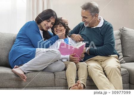 Grandson reading book to grandparents 30977099