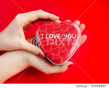 Red gift box heart-shaped in women's hands Red gift box heart-shaped in women's hands 30998895
