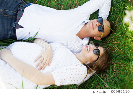 Happy couple woman and man lying on grass Happy couple woman and man lying on grass 30999110