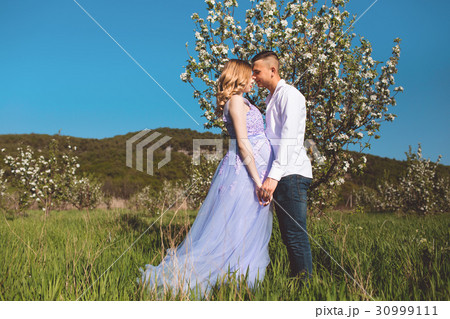 Happy couple woman and man in white blossom garden Happy couple woman and man in white blossom garden 30999111