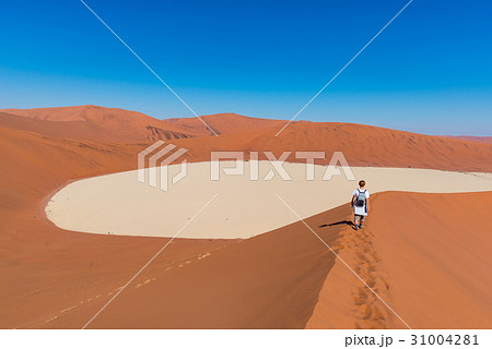 Tourist walking on the scenic dunes of Sossusvlei Tourist walking on the scenic dunes of Sossusvlei 31004281