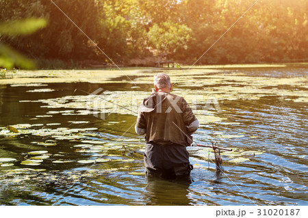 Old fisherman fishing in a lake or river with a 31020187