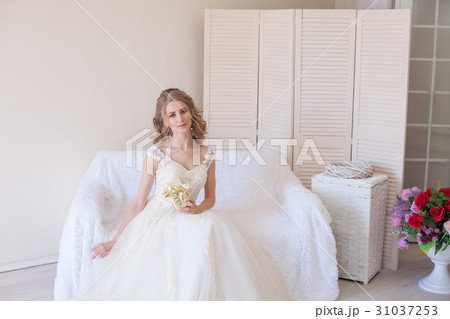 beautiful bride sitting on a white couch in 31037253