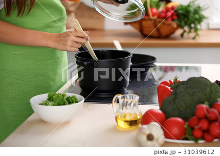 Young woman is cooking by the stove in the kitchen 31039612