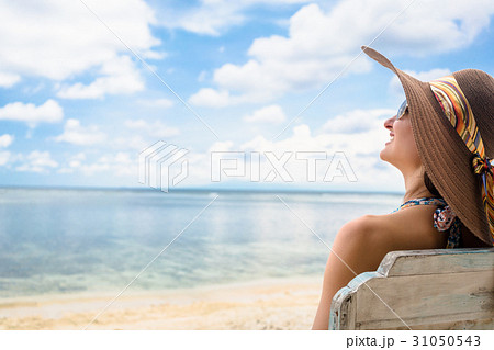 Female tourist relaxing in deck chair at beach in Female tourist relaxing in deck chair at beach in 31050543