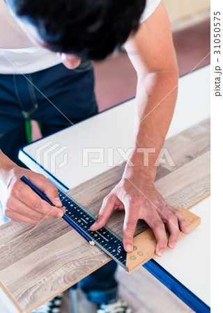 Carpenter marking cut on parquet piece Carpenter marking cut on parquet piece 31050575