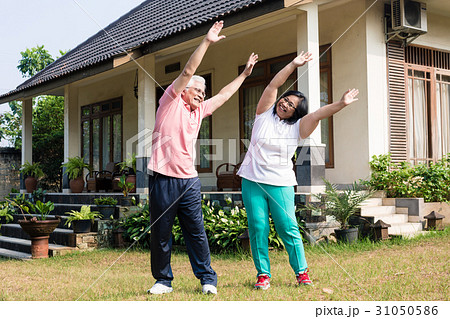 Active senior couple exercising with raised arms 31050586