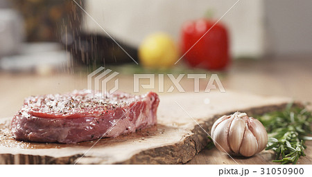 pepper falling on raw rib eye steak on board pepper falling on raw rib eye steak on board 31050900