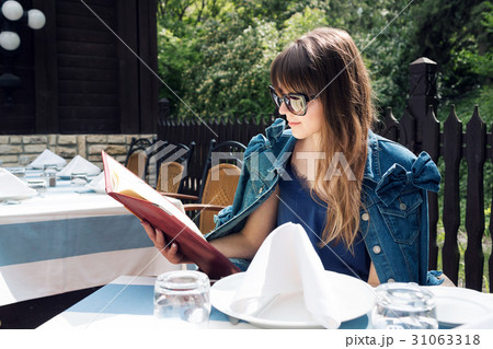 A smiling woman in a restaurant with the menu in A smiling woman in a restaurant with the menu in 31063318