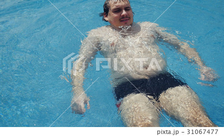 Bearded fat man swims on back along city view 31067477