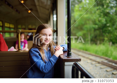 Happy little girl riding a train in a theme park Happy little girl riding a train in a theme park 31073353
