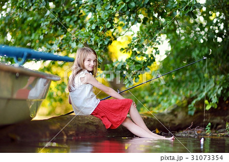 Cute little girl fishing with fishing rod by river Cute little girl fishing with fishing rod by river 31073354