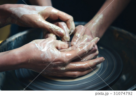 Two people mold a clay pot from white clay. 31074792