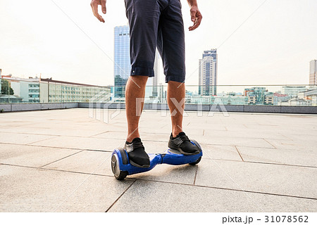 Legs on hoverboard, city background. 31078562