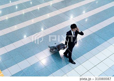 電話しながら空港の飛行機ロビーに向かうビジネスマン 俯瞰 フロア内 電話しながら空港の飛行機ロビーに向かうビジネスマン 俯瞰 フロア内 31080087