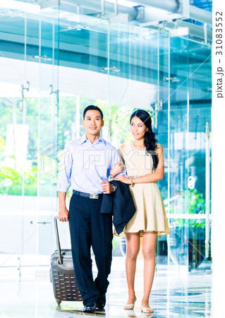Asian couple walking in hotel lobby with suitcase 31083552