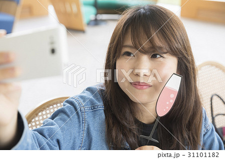 フォトプロップスを使って自撮りをする女子大生 撮影協力 日本経済大学の写真素材