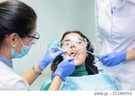 Two dentists working with patient. 31106453