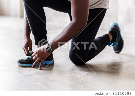 Young muscular athlete fixing his training shoe Young muscular athlete fixing his training shoe 31110298