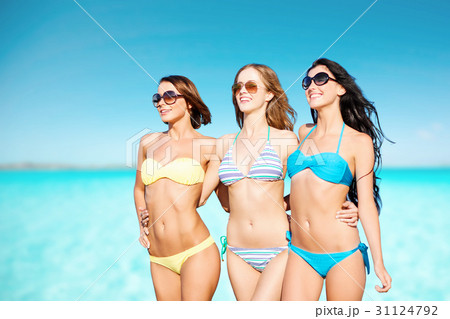 happy young women in bikinis over blue sky and sea happy young women in bikinis over blue sky and sea 31124792