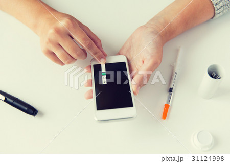 close up of woman with smartphone doing blood test close up of woman with smartphone doing blood test 31124998