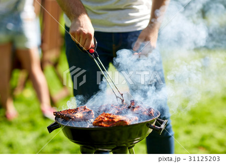 man cooking meat on barbecue grill at summer party 31125203